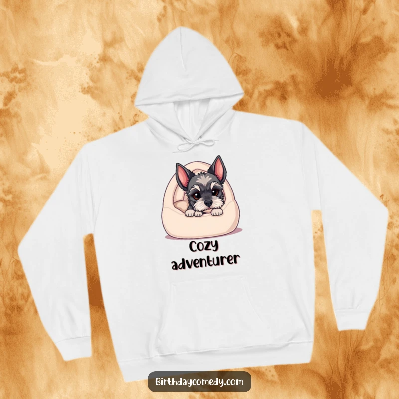 Funny hoodie with a schnauzer puppy peeking from a comfy dog bed, its bearded face exuding maximum charm and cuteness.