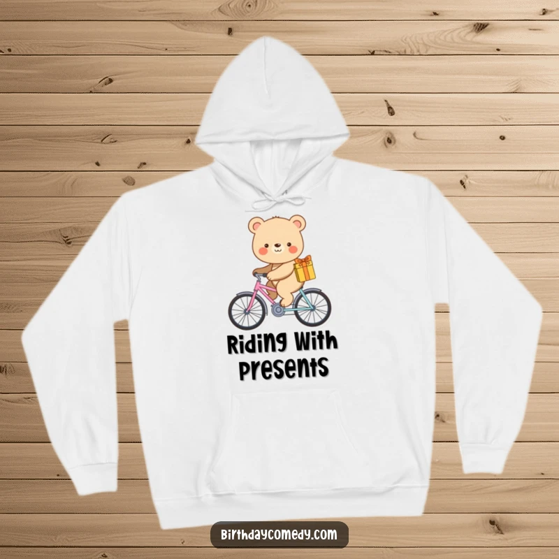 Funny hoodie featuring a smiling bear pedaling a tiny bicycle while carrying a gift.