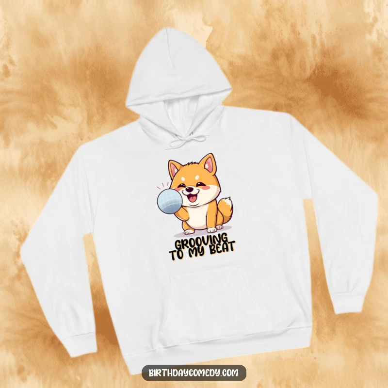 Funny Shiba Inu hoodie depicting a Shiba Inu with a determined grin, energetically batting at a shiny disco ball, full of life.