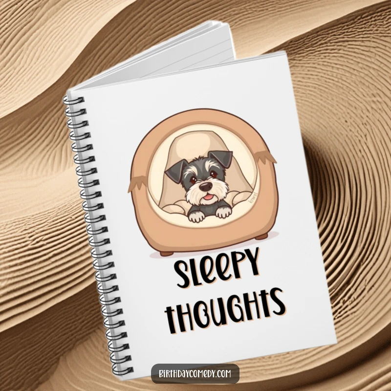 Funny schnauzer puppy notebook depicting a cute dog peeking from a cozy bed, ideal for jotting notes with humor.