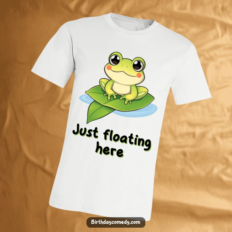 Funny frog t-shirt depicting a content frog with bulging eyes happily floating on a large leaf, ideal for casual wear.