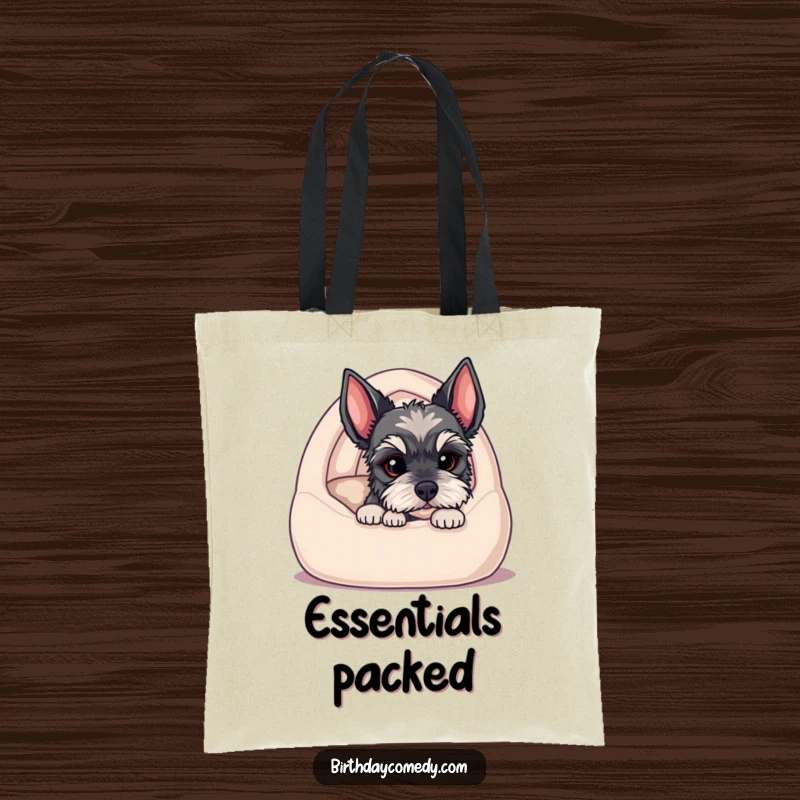 Funny tote bag illustrating a schnauzer puppy peeking from a cozy dog bed, capturing a moment of innocent curiosity and charm.
